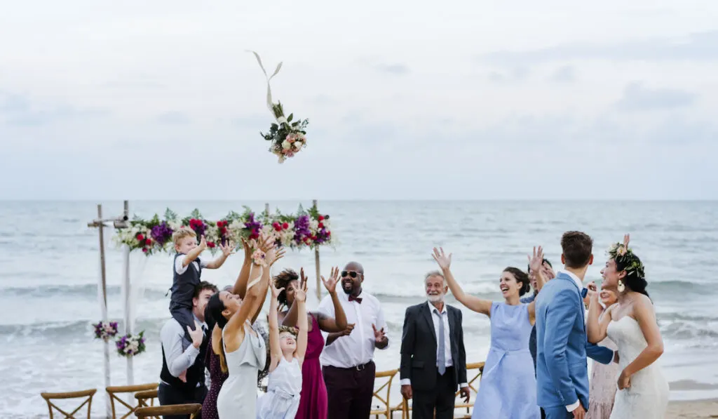 bride throwing boquet at beach wedding