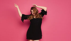 woman wearing a black dress on a pink background