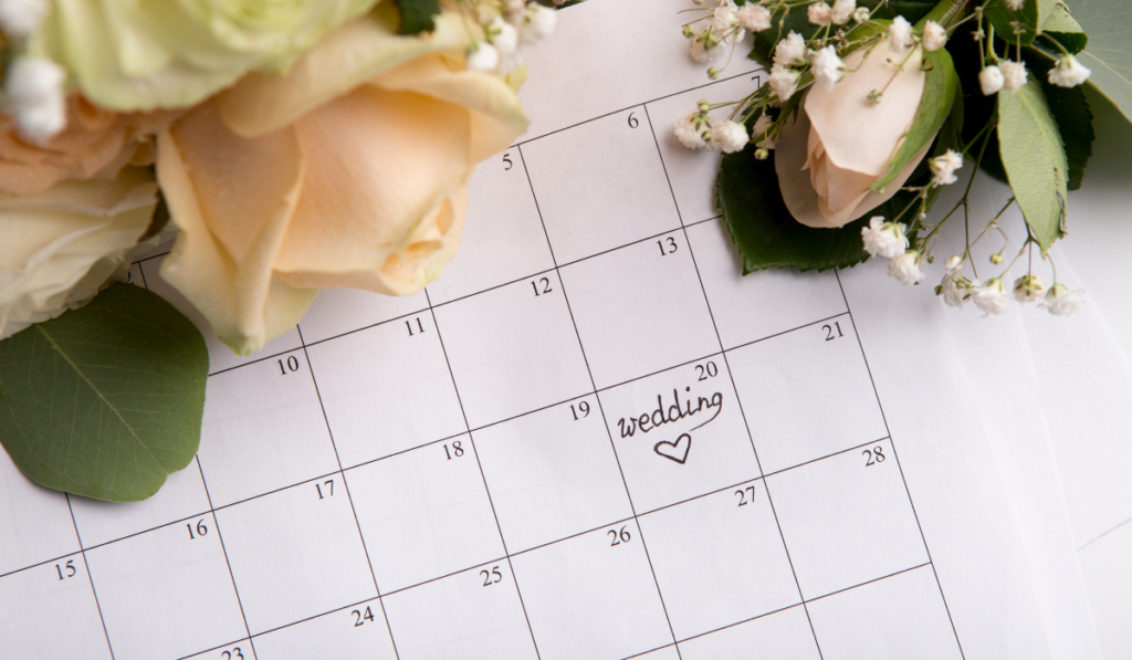 Choosing wedding date with pen writing heart on paper calendar