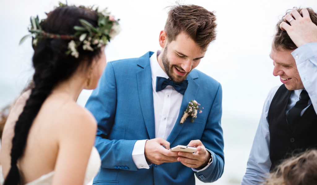 Groom occupied with phone at beach wedding ceremony
