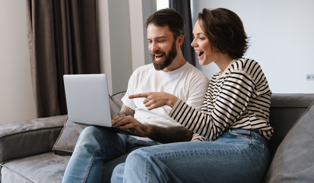 Happy young white couple looking at laptop computer