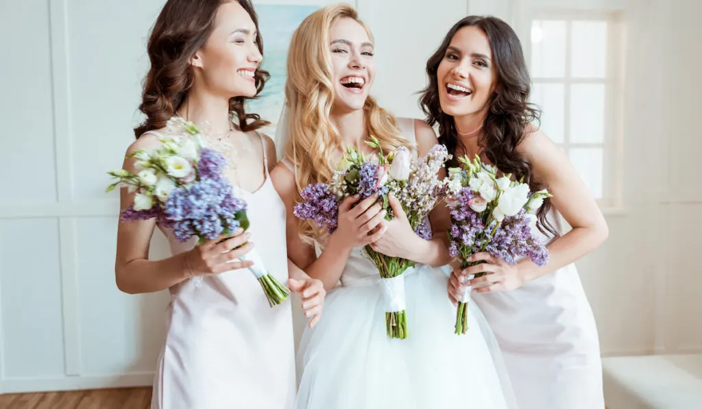 beautiful laughing bride with bridesmaids holding bouquets 