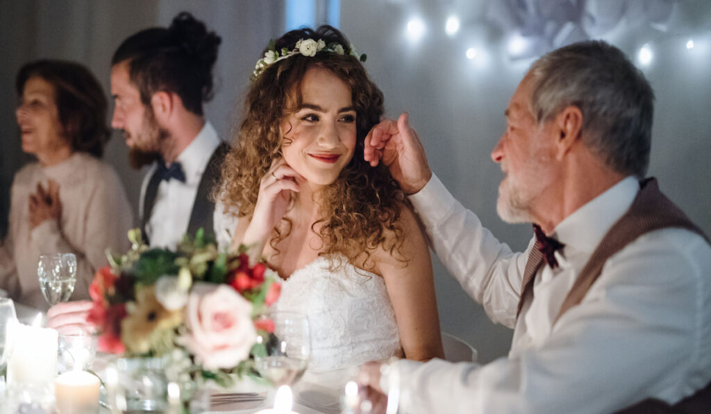 A loving father and beautiful bride sitting at the table on a wedding, talking 