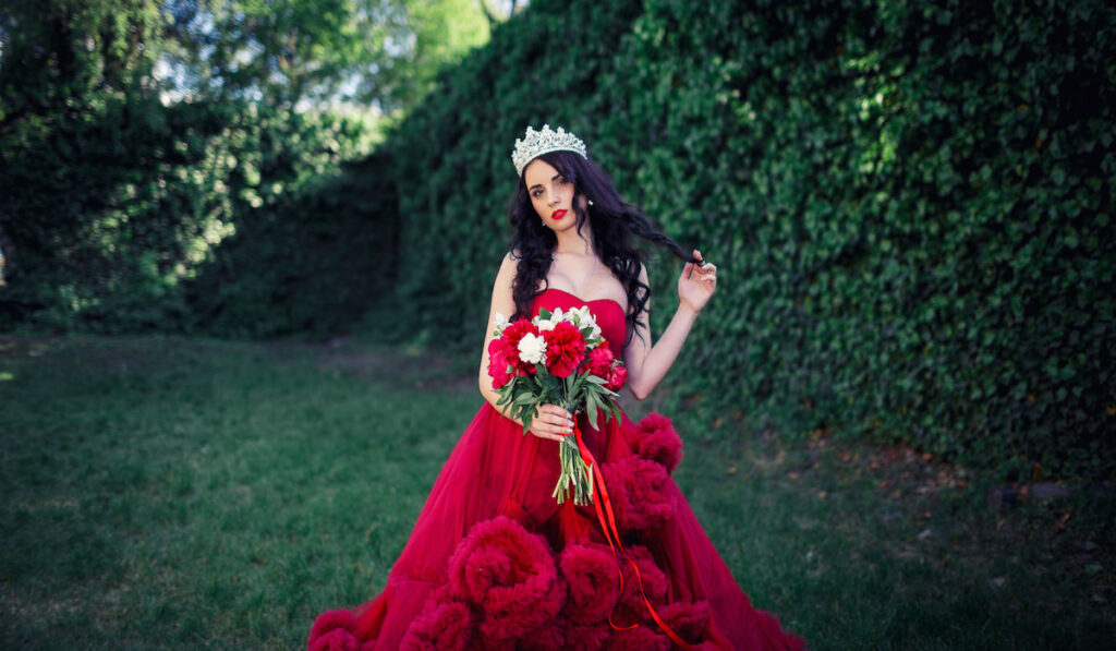 Beautiful bride wearing red wedding dress with crown and holding bouquet 