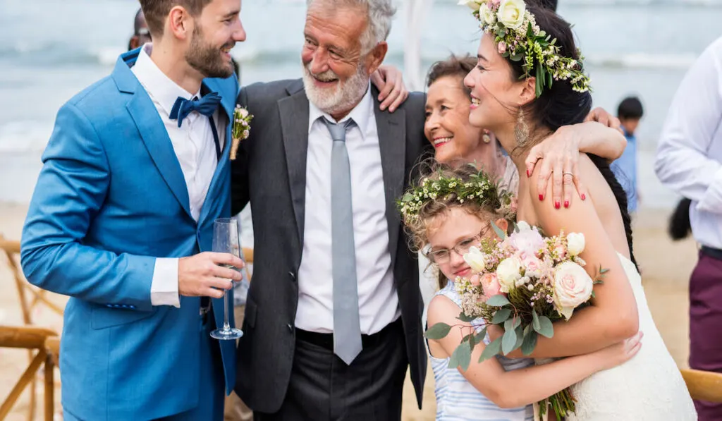 Bride, groom, and their parents in a wedding ceremony at the beach