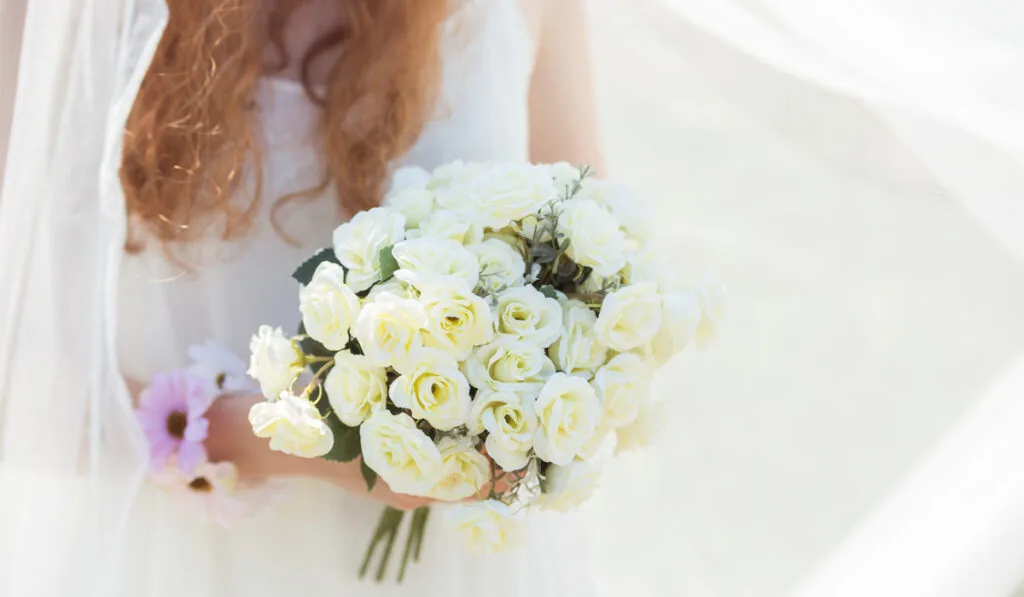 Bride holding a bunch of white roses