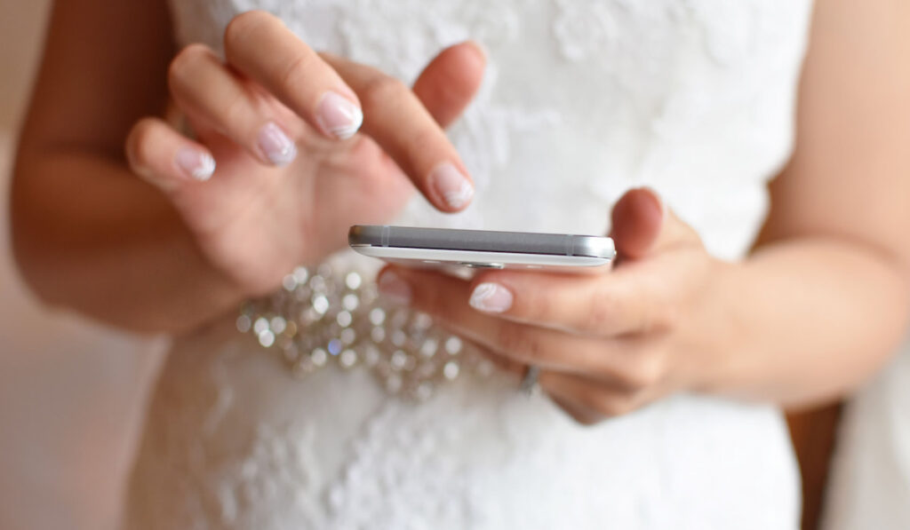 Bride in wedding dress holding smartphone in hands 