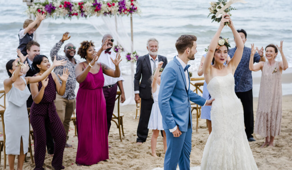 Bride throwing the bouquet at wedding on the beach