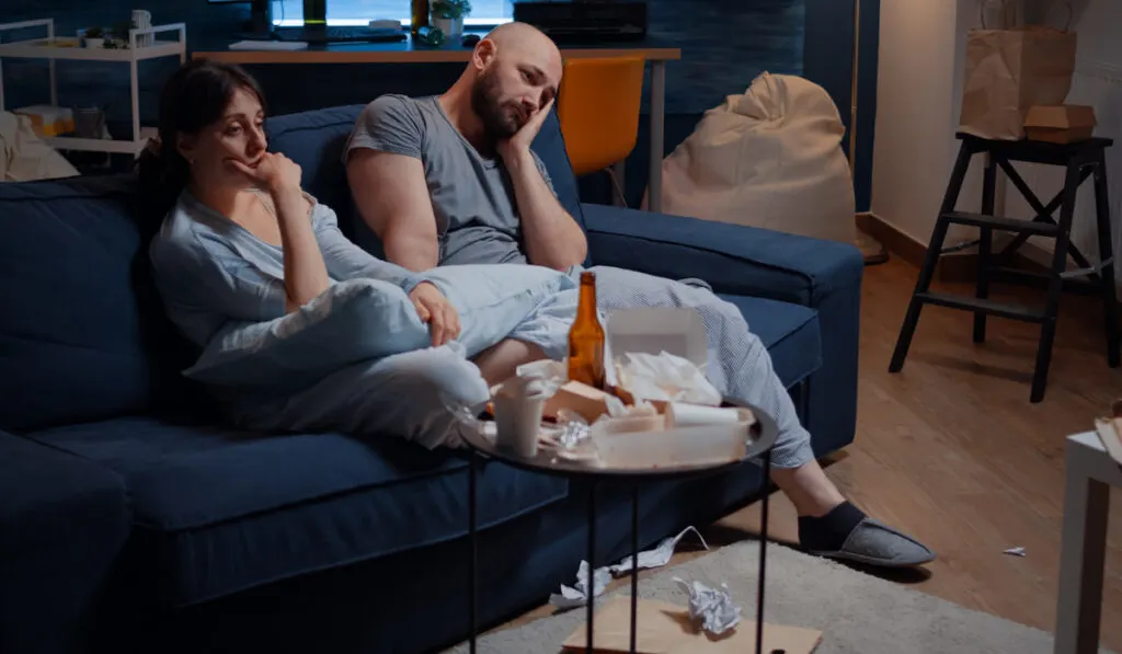 Frustrated young couple sitting in couch feeling disappointed
