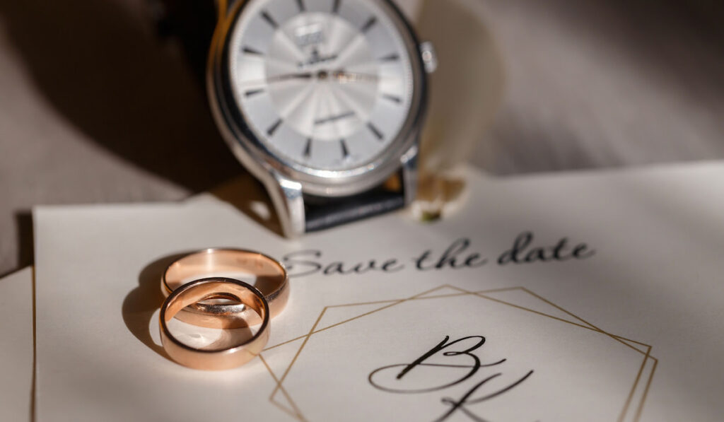 Gold wedding rings, a watch and save the date concept for wedding