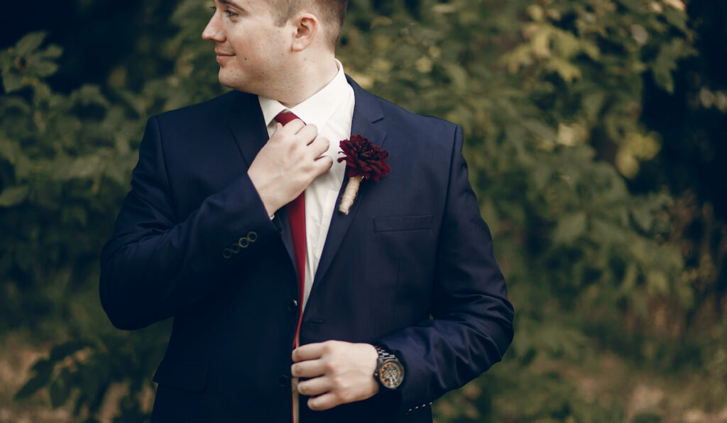 Groom in stylish suit with red boutonniere