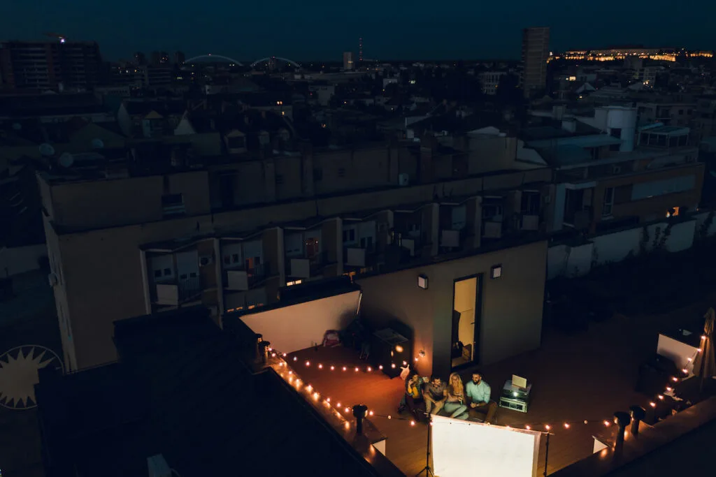 Group of friends watching movie during night time on the rooftop