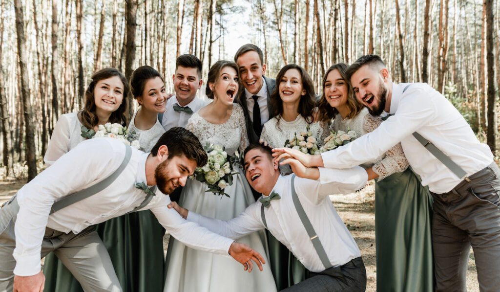 Group photo of happy newlyweds with their guests outdoor on the wedding day 