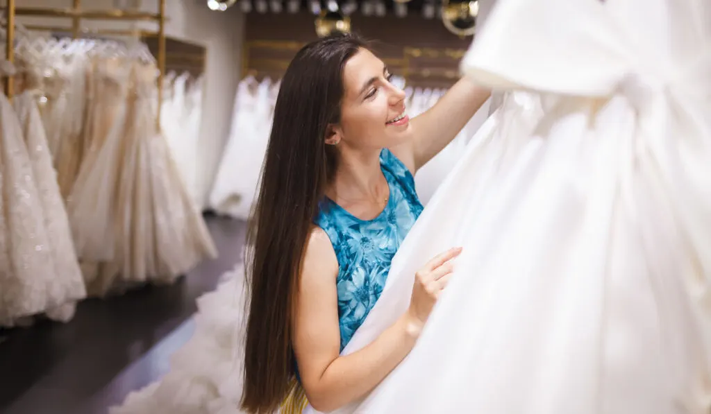 Happy bride chooses a dress in a wedding boutique
