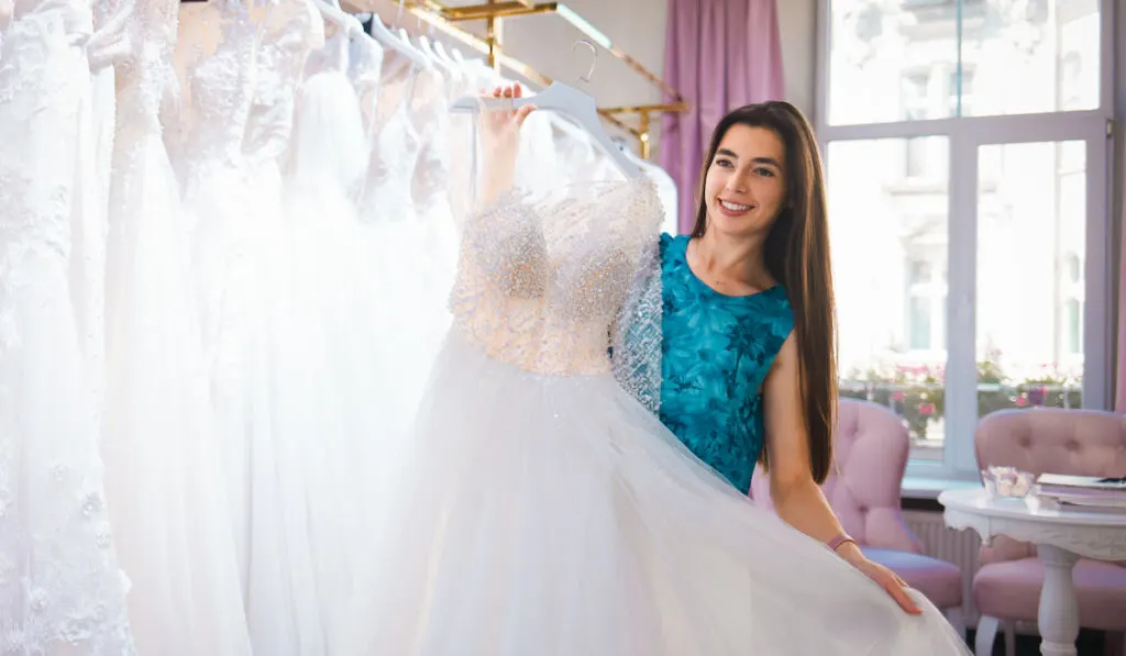 Happy bride chooses a dress in a wedding boutique
