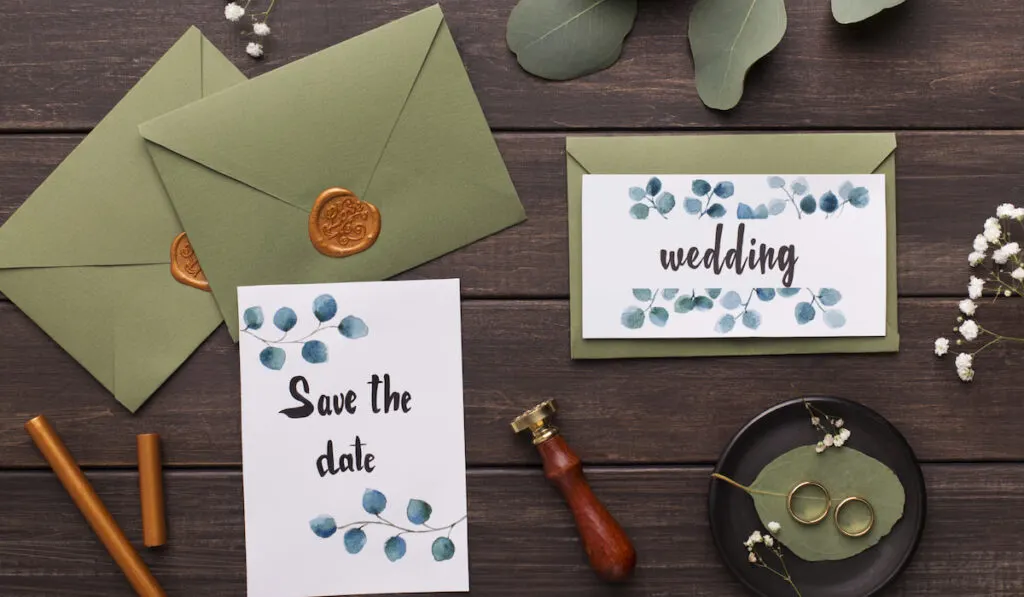 Preparing wedding invitations and folding envelopes on wood

