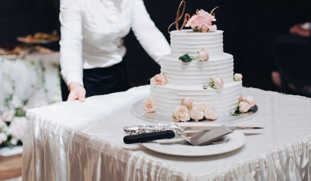 Waitress delivering modern wedding vanilla cake at wedding reception