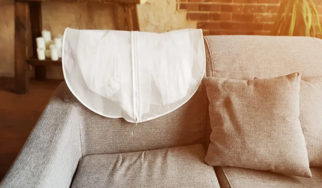 Wedding Dress in White Hanging Garment Bag on the back of the Couch