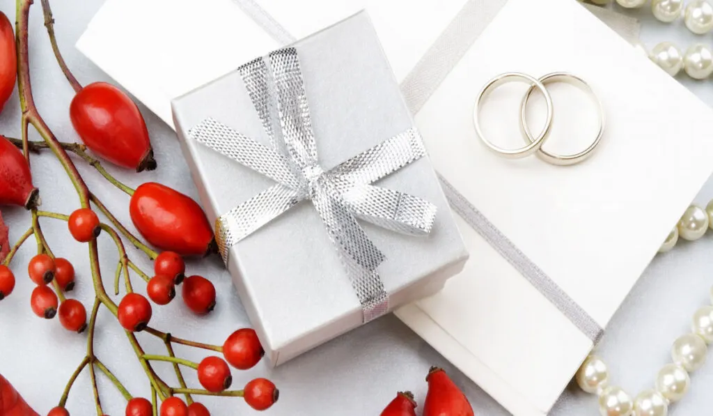 Wedding invitation with wedding rings, gift box, decorative rowan and pearls 
