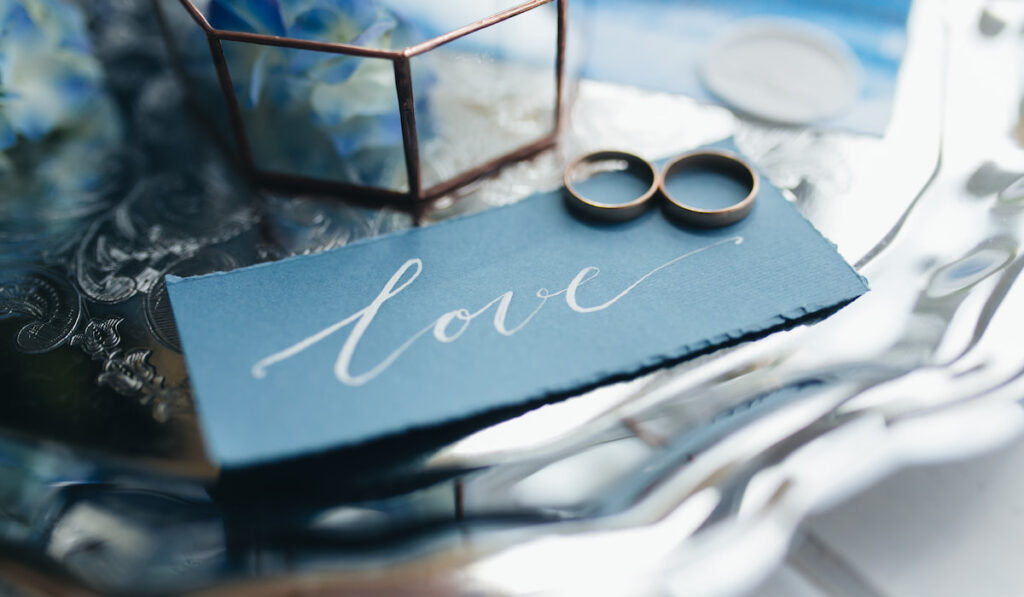Wedding rings and wedding invitation with word love on the table