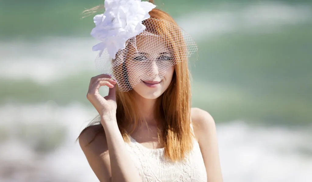 Young bride at the beach wearing birdcage veil