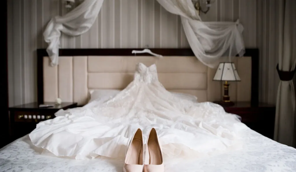 a bride's wedding shoes and wedding dress on the bed 