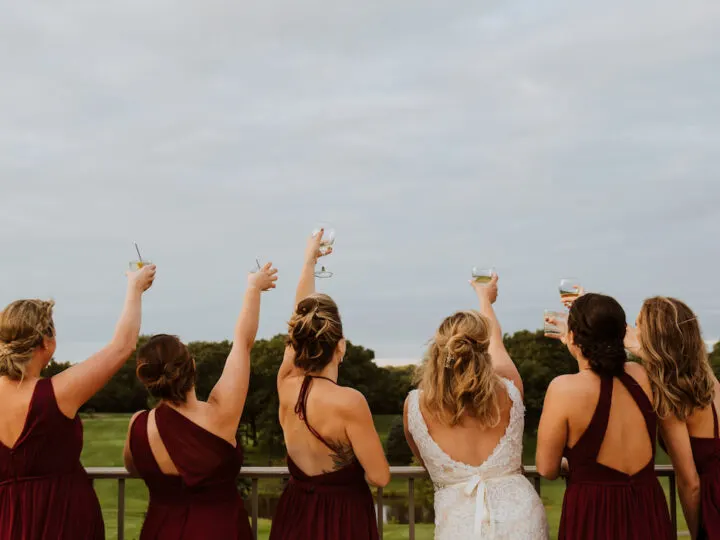 bride and her bridesmaids cheers-ing the sky at a golf course wedding