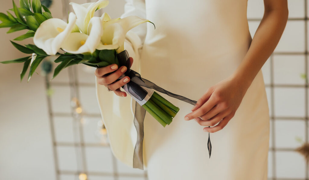 bride holding bouquet of white calla lilies 