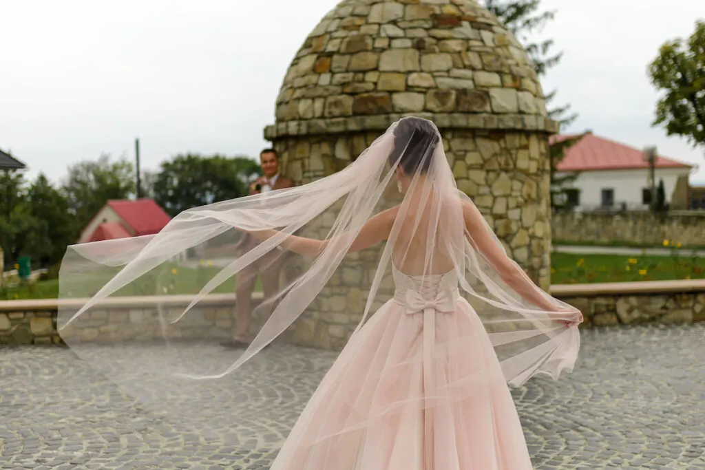 bride holding  her veil going to her groom