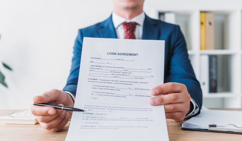 cropped view of manager pointing with pen at loan agreement
