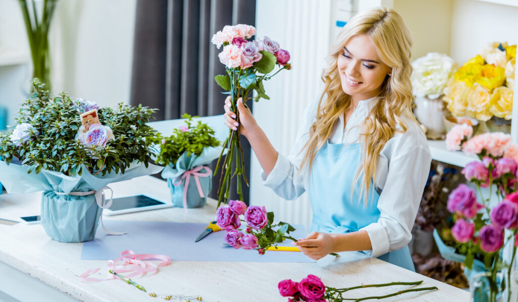 female florist in apron arranging flowers