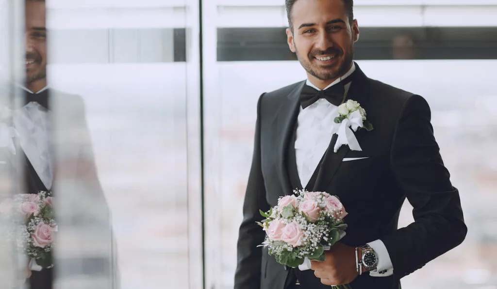 groom with Boutonniere on his suit and holding bridal bouquet