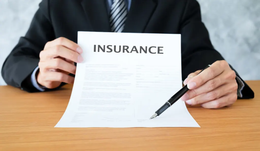 man holding insurance policy and a pen to sign the document