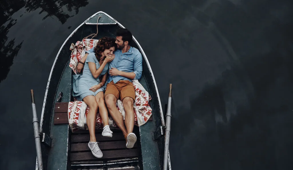 quality time together. Top view of beautiful young couple embracing and smiling while lying in the boat