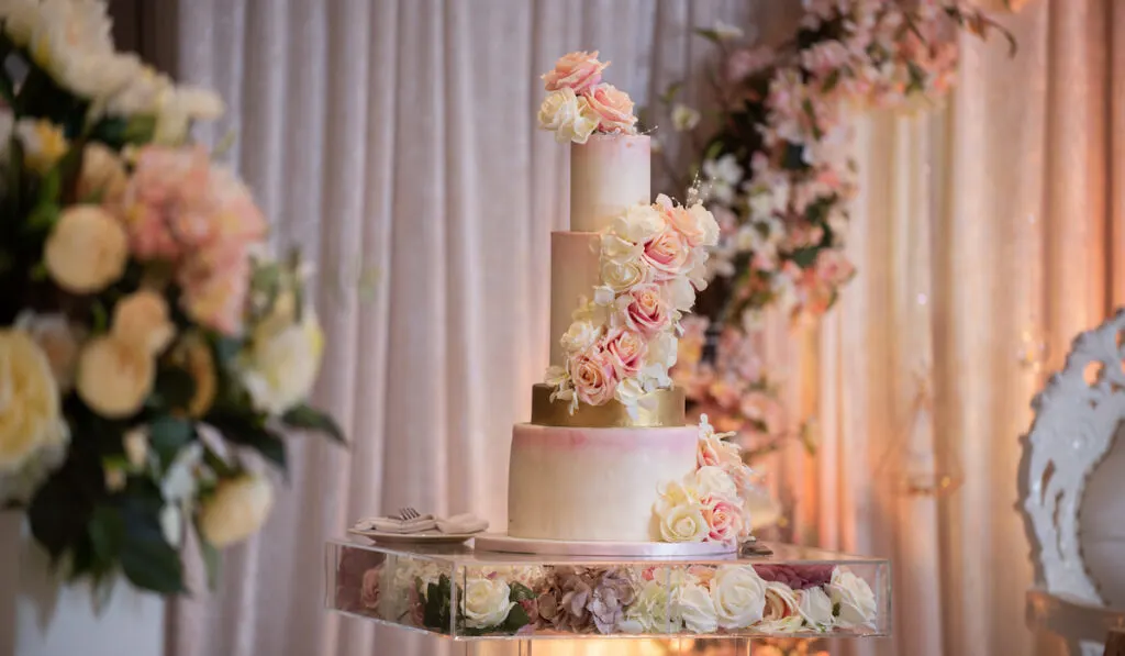 white and pastel pink wedding cake with beautiful flowers on wedding reception