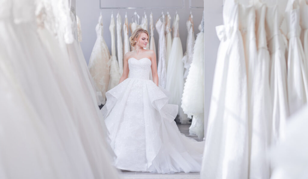 woman fitting beautiful white wedding dress in a wedding boutique