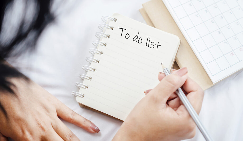 woman hand writing words to do list on notepad with calendar