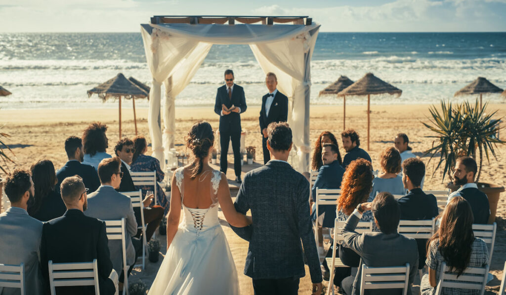 Bride walking down the aisle with her father, start of the wedding ceremony on the beach