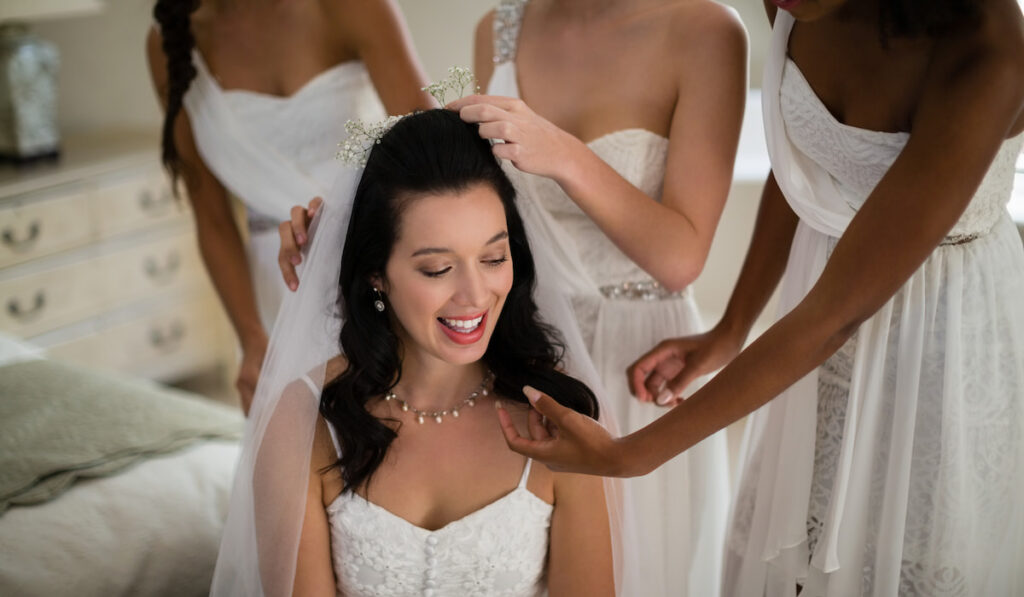 Bridesmaid assisting bride in getting ready for wedding ceremony