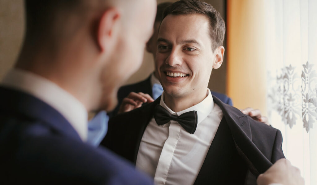Groom getting ready in the morning with groomsmen in the room
