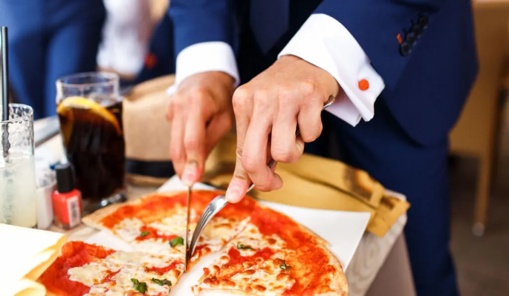Man in suit eating pizza while waiting in the room