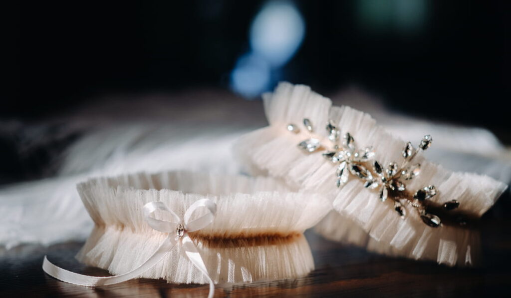 Two white garters of the bride are lying on the table