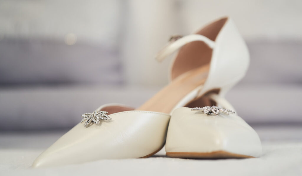 White shoes with brooch on blurry background