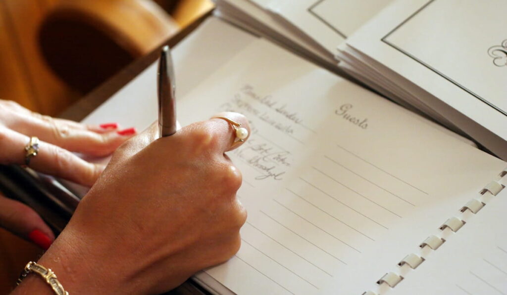 Womans hand signing a guest book with a pen