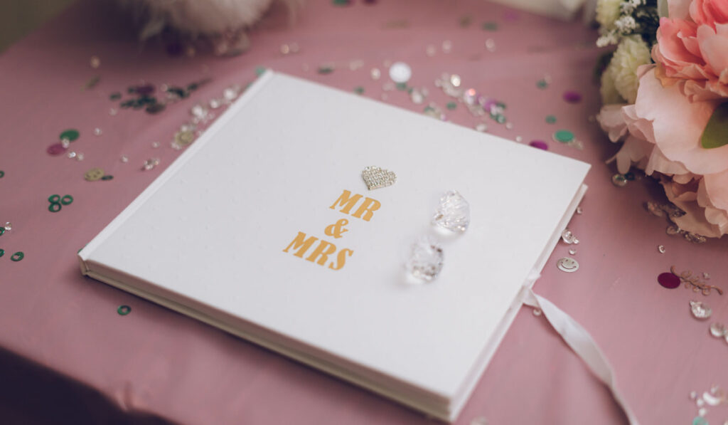 a wedding guest book with Mr and Mrs written on the cover surrounded by glitter and decoration