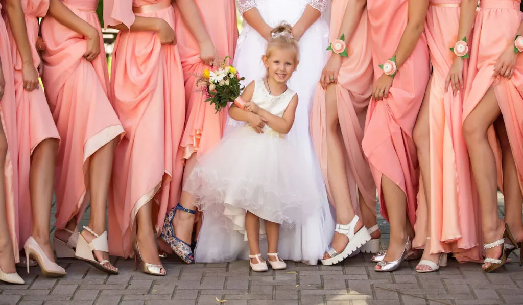 bride, bridesmaid, and little girl on pose showing their stylish shoes 