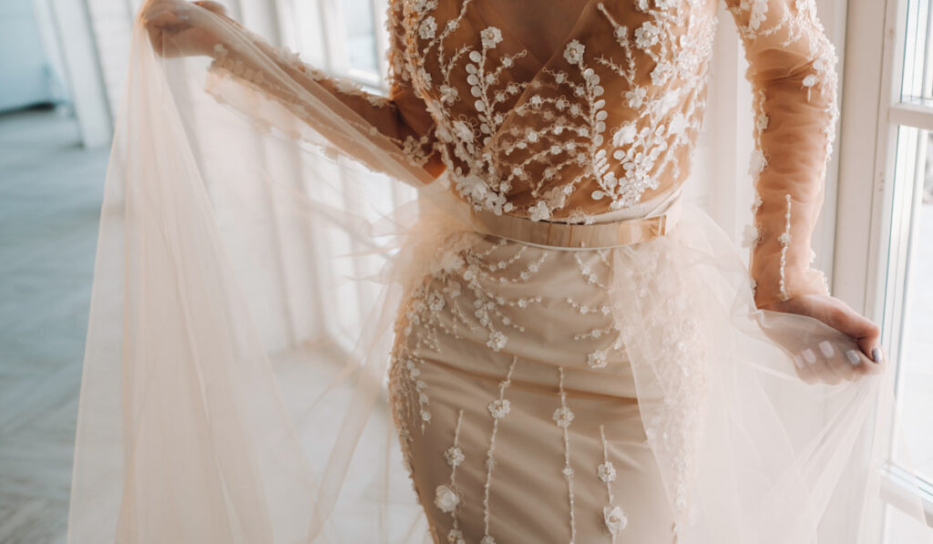 A luxurious bride in a wedding dress with gold waistband posing