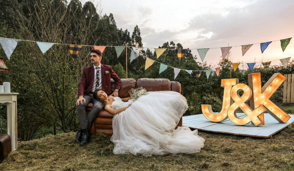 Bride lying over sofa with groom in the field
