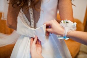 Morning of the bride preparation. Young and handsome bride at wedding day. Bridesmaid tie bow.