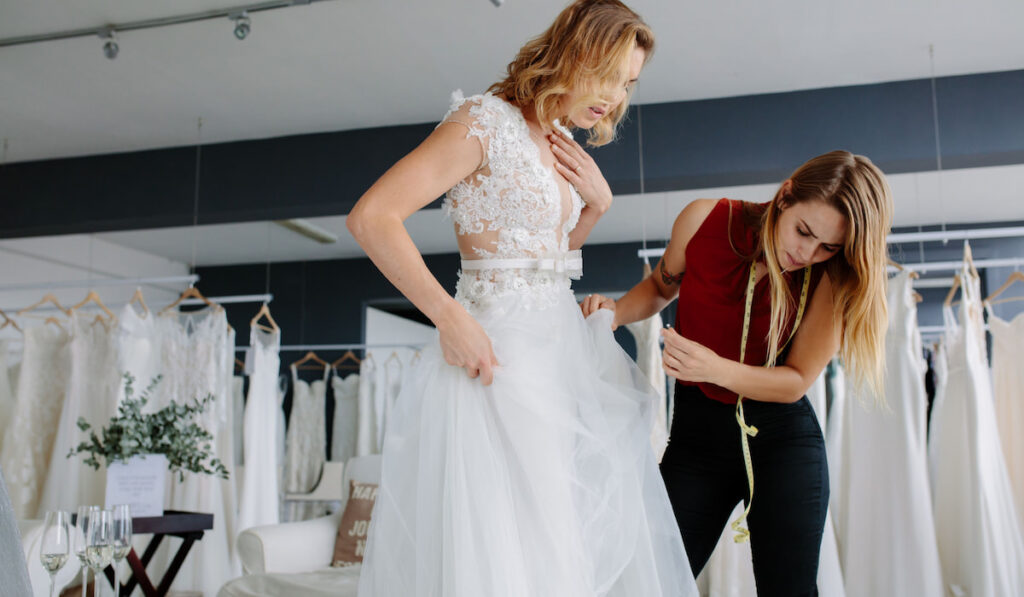 Female making adjustment to wedding gown in fashion designer studio